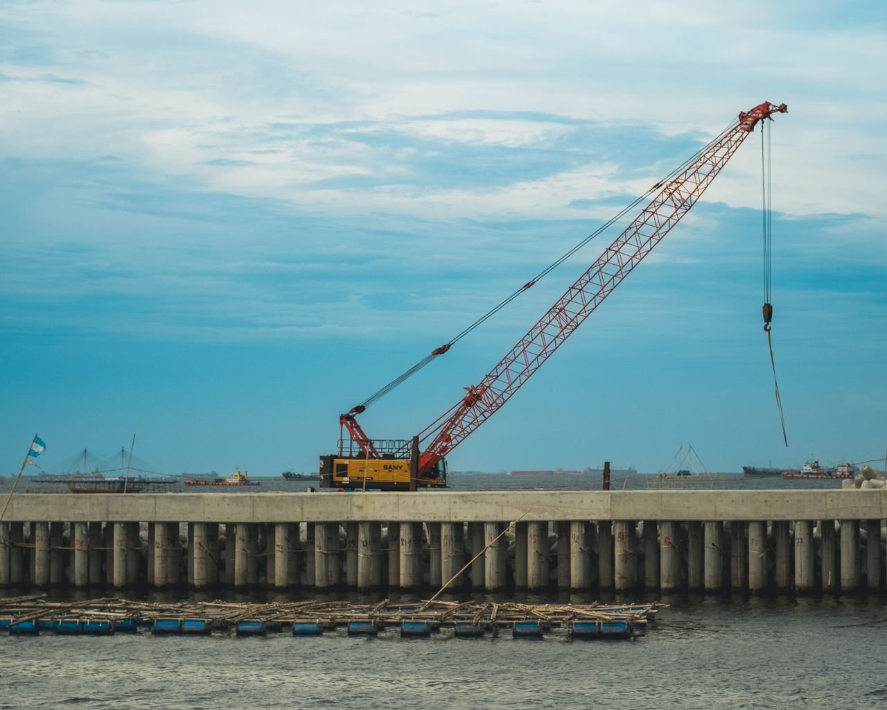 A construction crane on a dock under a blue sky, symbolizing industrial progress.
